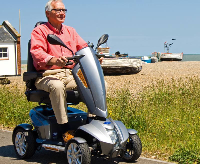 This mid-sized 4-wheel scooter is cool, compact and clever. As with all the Vita family it includes state-of-the-art styling ideal for people looking for a more contemporary look. Its streamlined design ensures nimble handling however comfort is still maximised with an orthopaedic adjustable seat and ample leg room.
The TGA Vita Midi provides an exceptionally smooth and stable ride through its advanced suspension. Journeys around town or in the country can be safe and enjoyable as this remarkable scooter will glide over uneven terrain. With smart energy saving LED lights the Vita Midi gives up to 22 miles on a single charge – ample for any rewarding outdoor experience.