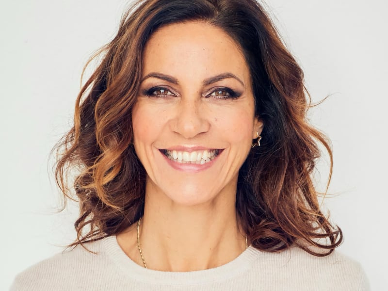 Julia Bradbury smiling into the camera, she wears an ecru top and her eyes sparkle with health and wellbeing.